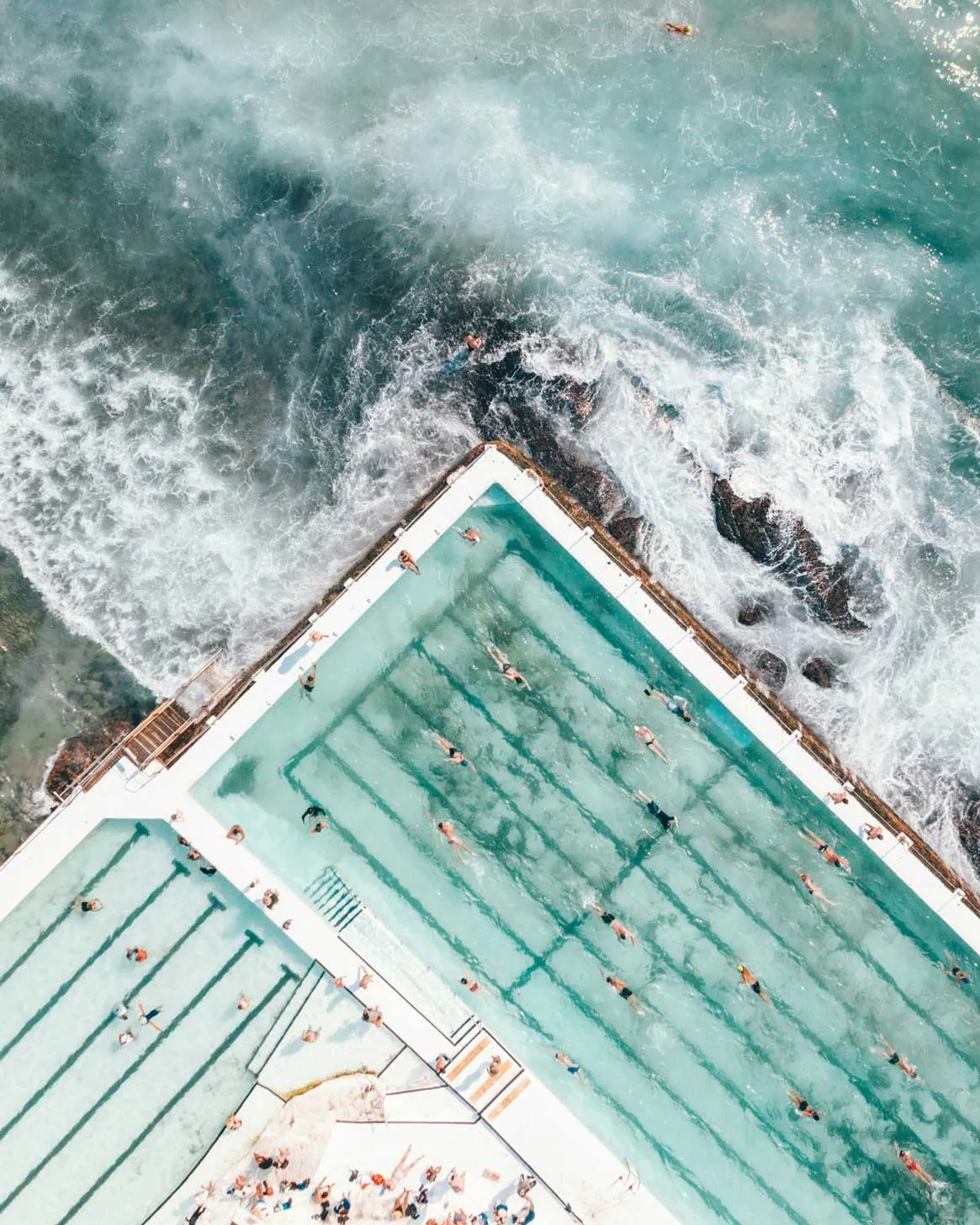 Schwimmbad an Küste mit schwimmenden Menschen